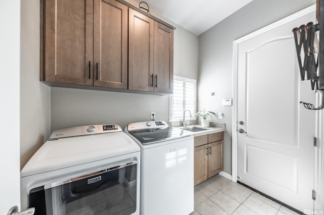 laundry room featuring cabinet space, light tile patterned floors, separate washer and dryer, and a sink