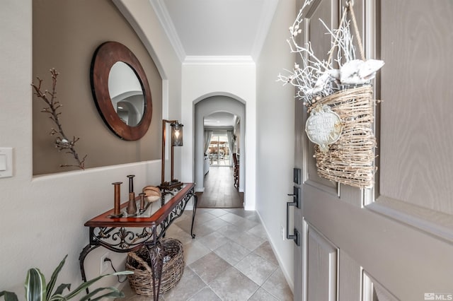 entrance foyer with arched walkways, light tile patterned flooring, baseboards, and ornamental molding