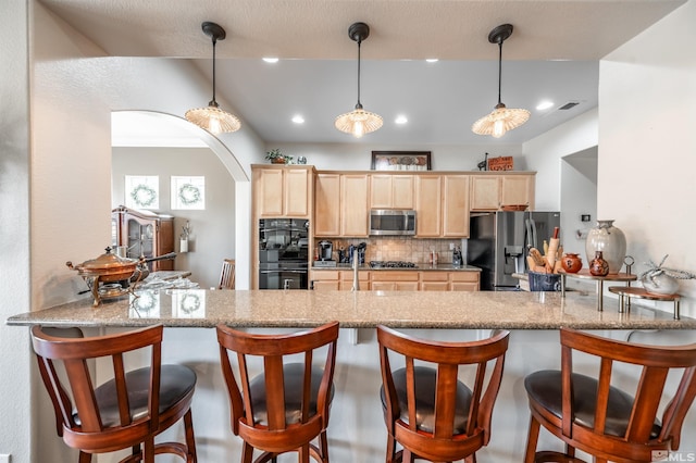 kitchen featuring light brown cabinets, backsplash, appliances with stainless steel finishes, and a peninsula