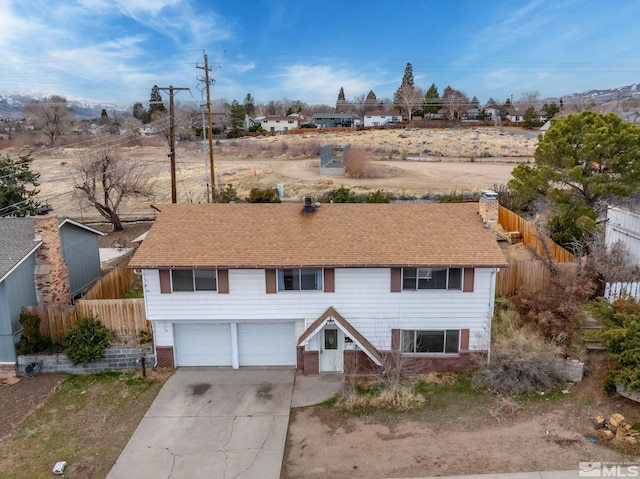 view of front of property with concrete driveway, an attached garage, fence, and a chimney