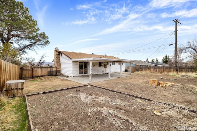 back of property with a fenced backyard, a chimney, and a patio