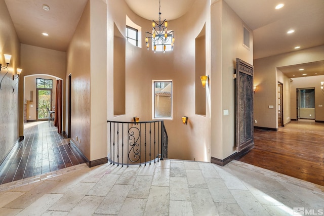 hallway featuring recessed lighting, arched walkways, an inviting chandelier, and stone tile floors