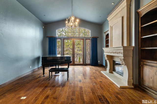 sitting room featuring a glass covered fireplace, a notable chandelier, lofted ceiling, and wood-type flooring