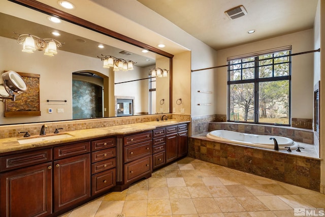 bathroom with a sink, visible vents, a bath, and double vanity