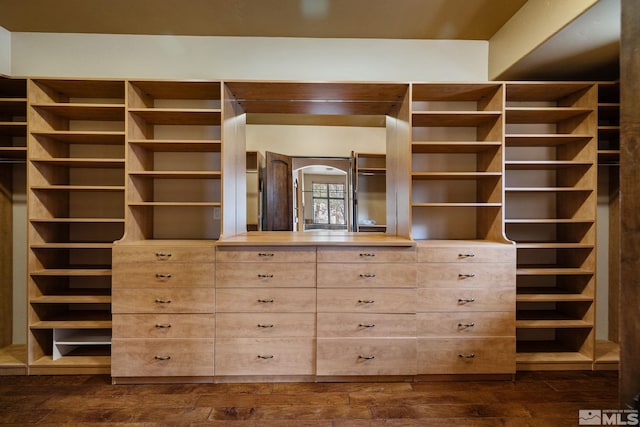 walk in closet with dark wood-style floors