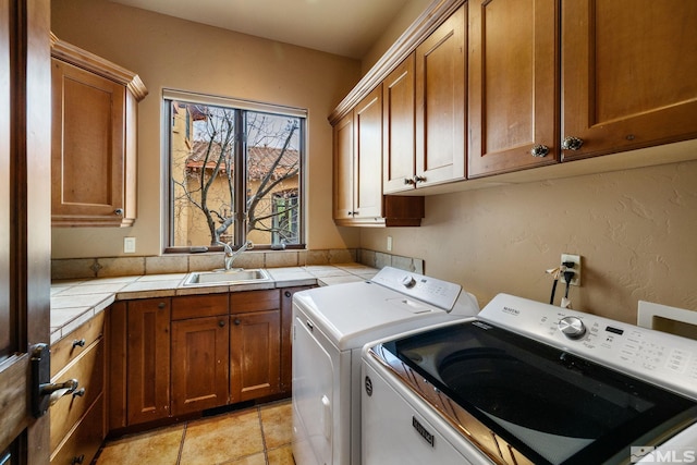 clothes washing area featuring a sink, cabinet space, and washer and clothes dryer