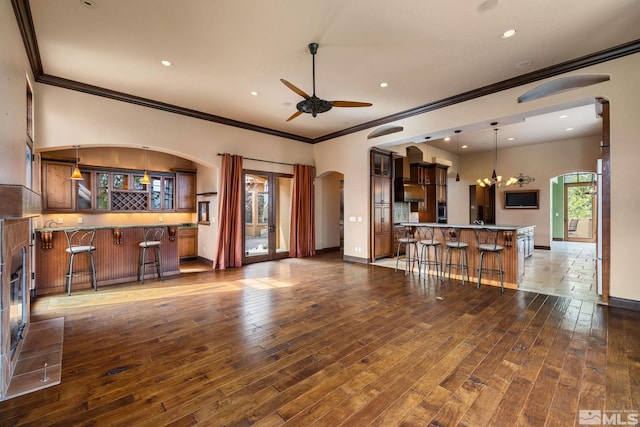 living room featuring a ceiling fan, baseboards, wet bar, arched walkways, and dark wood-style flooring