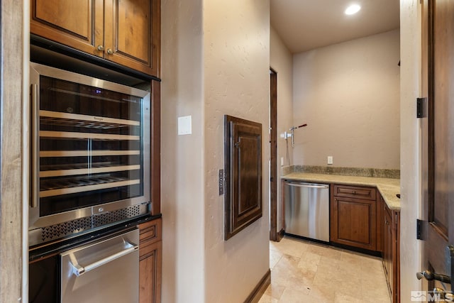 kitchen with beverage cooler, light countertops, dishwasher, a warming drawer, and a textured wall