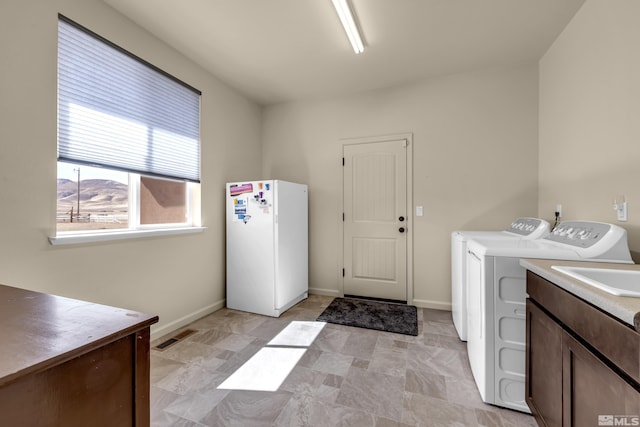 laundry room with visible vents, cabinet space, separate washer and dryer, and baseboards