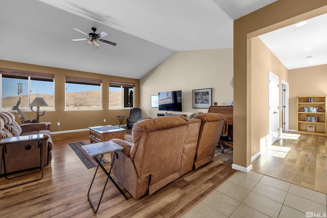 living room featuring vaulted ceiling, light wood-style flooring, baseboards, and ceiling fan