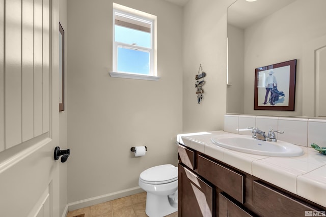 bathroom with toilet, vanity, and baseboards