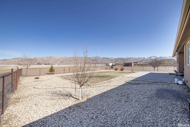 view of yard featuring a patio area, a fenced backyard, and a mountain view