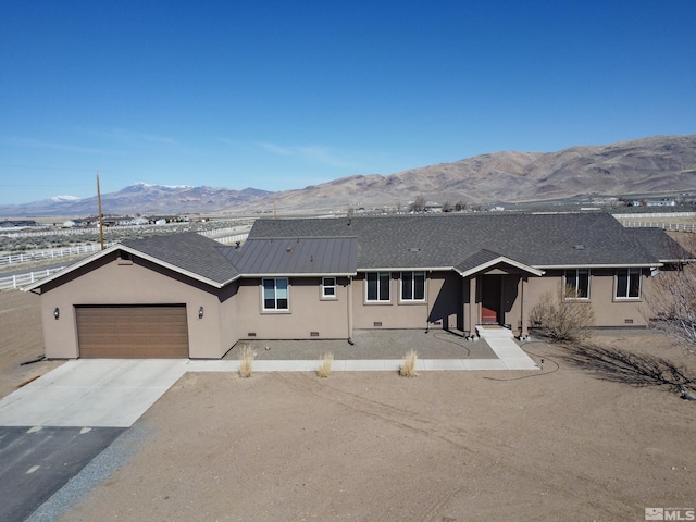 ranch-style home featuring concrete driveway, roof with shingles, stucco siding, a garage, and a mountain view