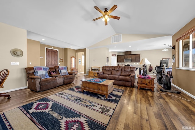 living area with visible vents, baseboards, lofted ceiling, wood finished floors, and a ceiling fan