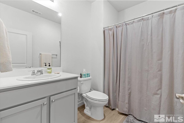 bathroom featuring visible vents, toilet, a shower with curtain, wood finished floors, and vanity