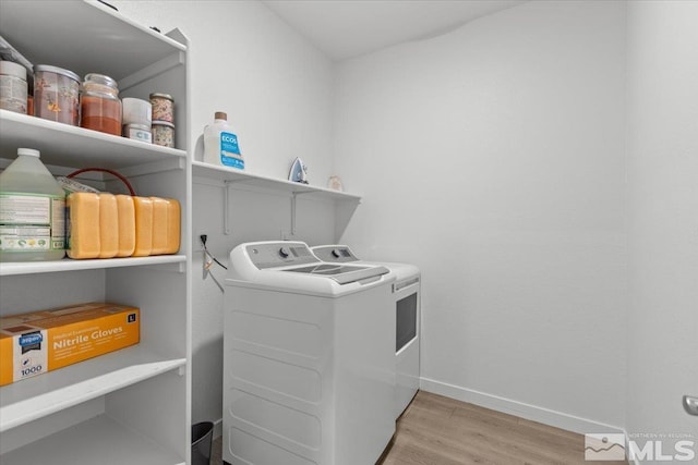 laundry room featuring laundry area, baseboards, light wood-style floors, and separate washer and dryer