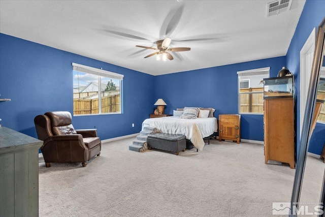 carpeted bedroom with a textured ceiling, a ceiling fan, visible vents, and baseboards