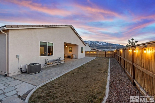 back of property with a patio, a fenced backyard, stucco siding, central air condition unit, and a mountain view