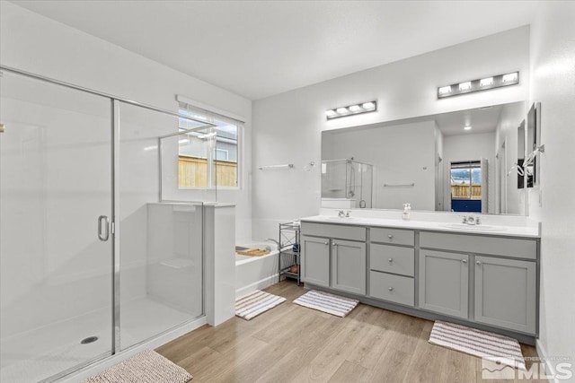 full bath with a shower stall, a bath, wood finished floors, and a sink