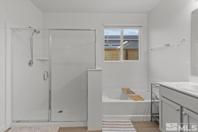 bathroom featuring a bath, a shower stall, vanity, and wood finished floors