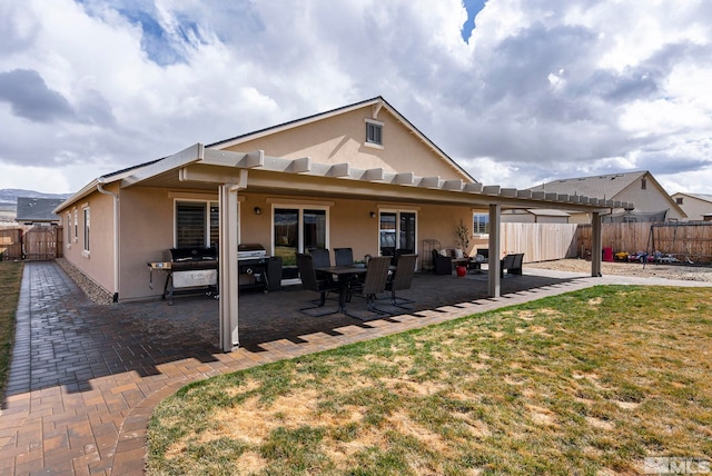 back of property featuring stucco siding, a lawn, a fenced backyard, and a patio area