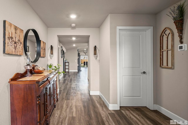 hallway featuring dark wood-type flooring and baseboards