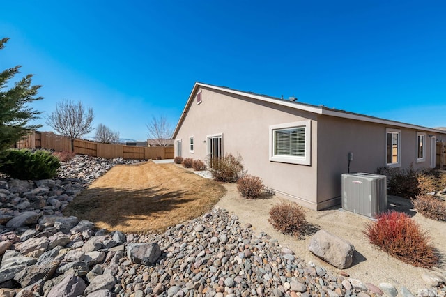 view of home's exterior with central air condition unit, fence, and stucco siding