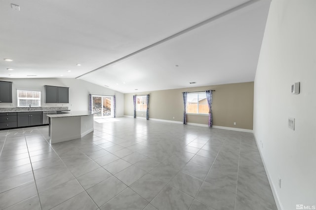 unfurnished living room featuring a sink, lofted ceiling, and a healthy amount of sunlight