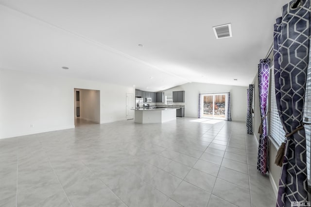 unfurnished living room with light tile patterned floors, visible vents, baseboards, and vaulted ceiling