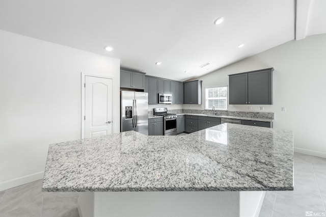 kitchen with appliances with stainless steel finishes, light stone countertops, gray cabinetry, and a sink