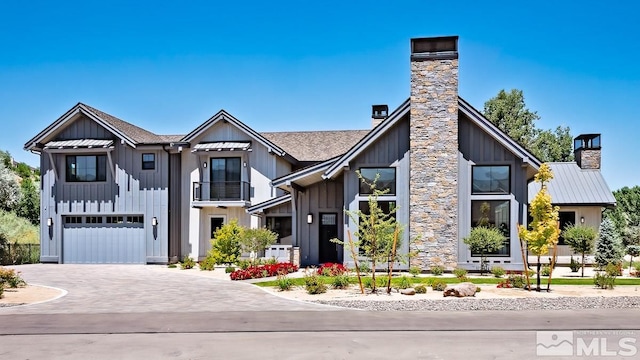 modern inspired farmhouse featuring an attached garage, board and batten siding, driveway, and a chimney