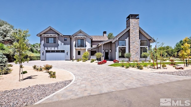 view of front of house featuring curved driveway, board and batten siding, a chimney, and an attached garage