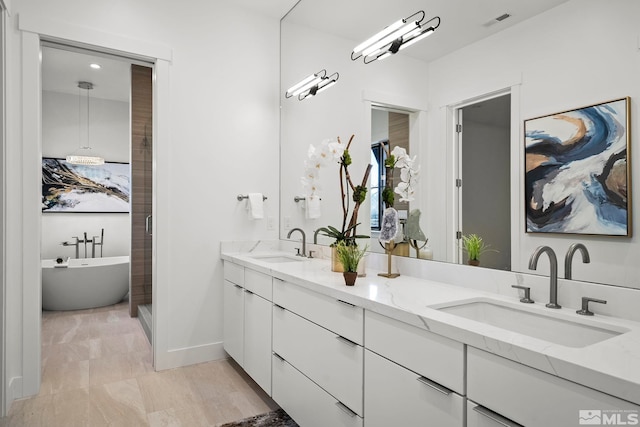 full bath featuring a freestanding bath, double vanity, visible vents, and a sink