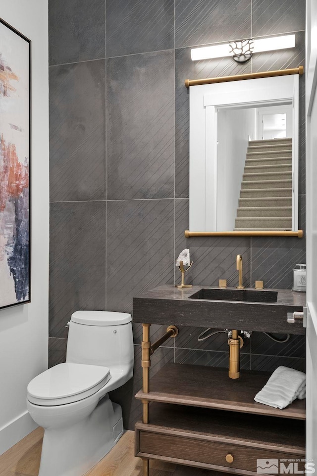 bathroom featuring tile walls, toilet, and a sink