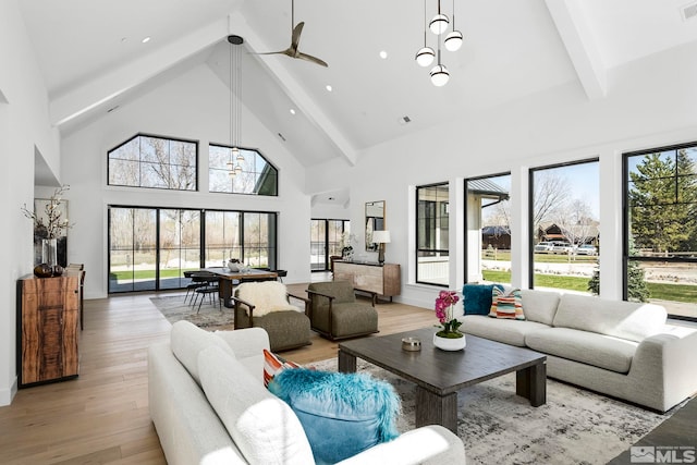 living area featuring beam ceiling, high vaulted ceiling, light wood-style flooring, and a ceiling fan