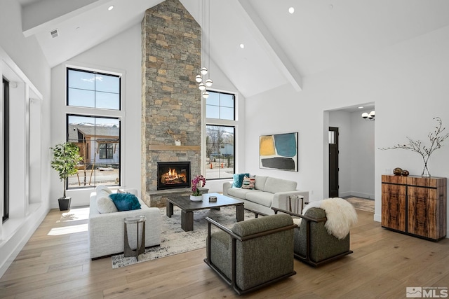 living area with visible vents, beam ceiling, high vaulted ceiling, hardwood / wood-style floors, and a stone fireplace