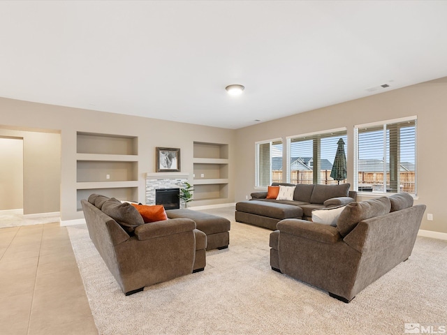 living area with tile patterned flooring, visible vents, built in shelves, baseboards, and a fireplace