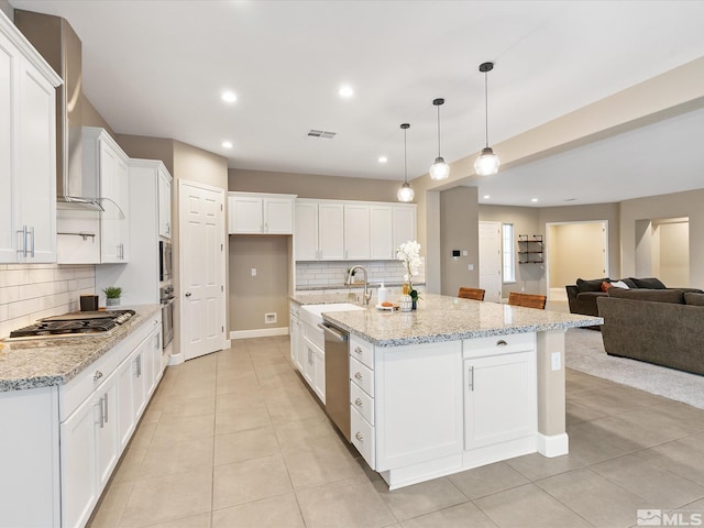 kitchen featuring visible vents, a sink, open floor plan, white cabinetry, and stainless steel appliances