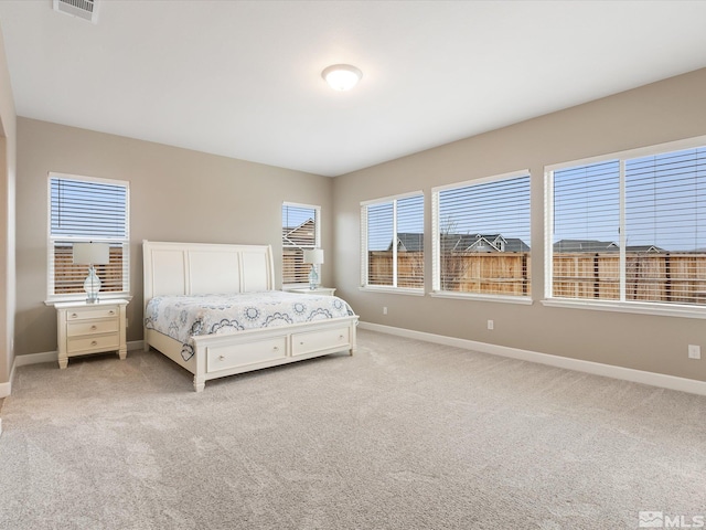 bedroom featuring multiple windows, light colored carpet, and baseboards