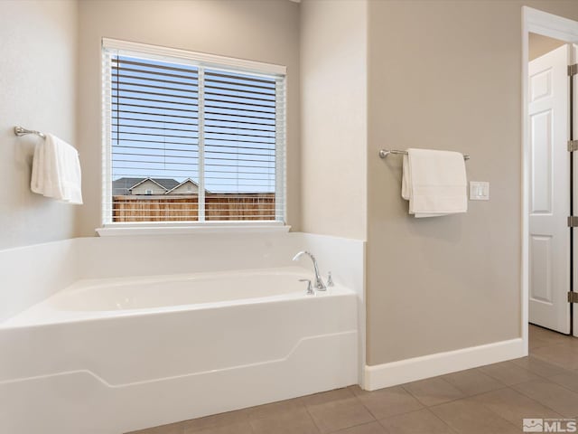 bathroom with tile patterned flooring, a bath, and baseboards