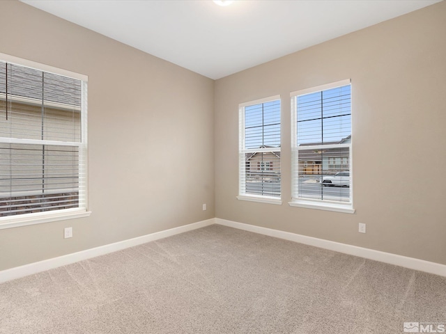 carpeted spare room featuring baseboards