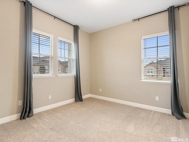 spare room featuring baseboards and light carpet