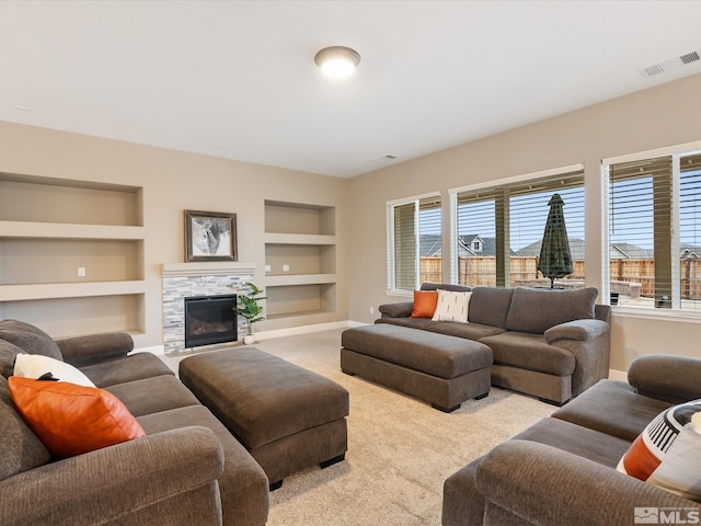 living area featuring visible vents, a tiled fireplace, built in features, carpet, and baseboards