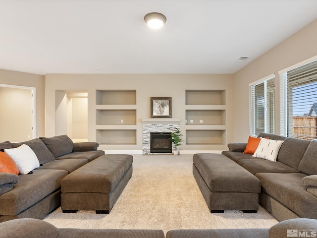 living room with a tiled fireplace, built in features, carpet, and visible vents