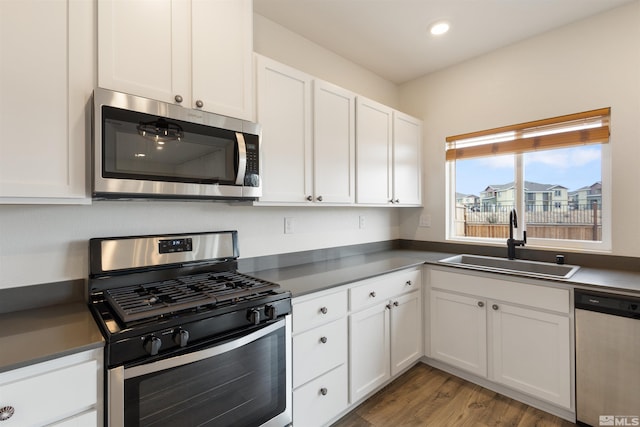 kitchen with white cabinetry, dark countertops, appliances with stainless steel finishes, and a sink