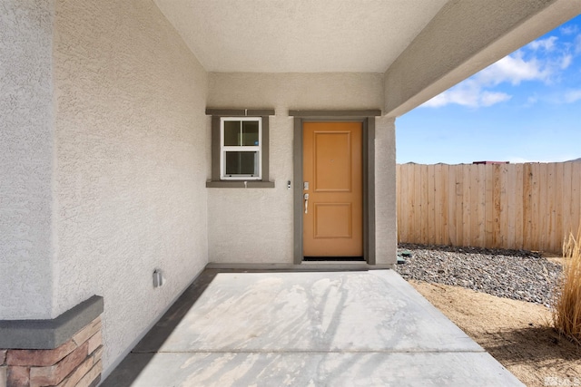 property entrance featuring stucco siding, a patio, and fence