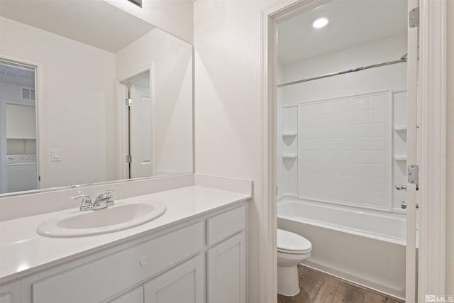 bathroom featuring visible vents, toilet, vanity, wood finished floors, and washer / clothes dryer