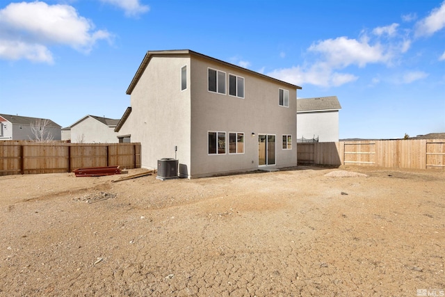 back of house featuring central AC unit, a fenced backyard, and stucco siding