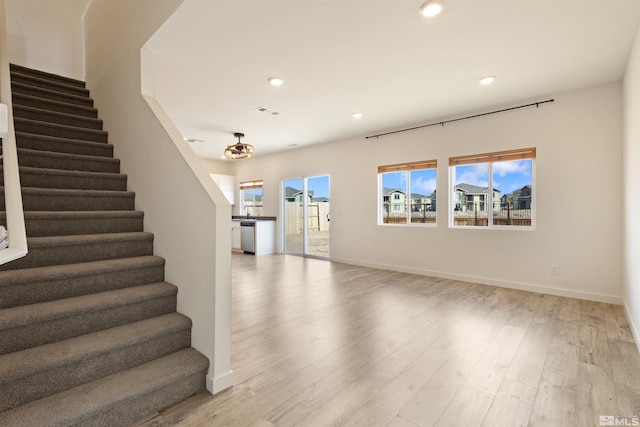 unfurnished living room with light wood finished floors, recessed lighting, stairs, and baseboards