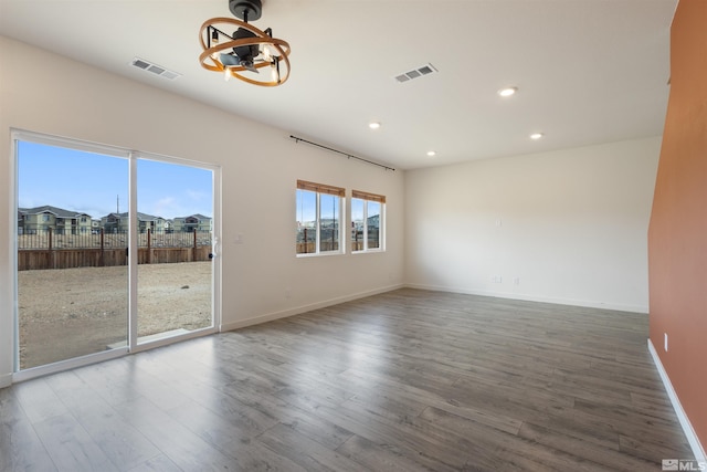 spare room with visible vents, a notable chandelier, and wood finished floors